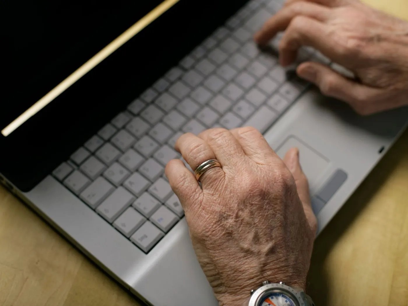 Twee handen typen op het toetsenbord van een laptop.