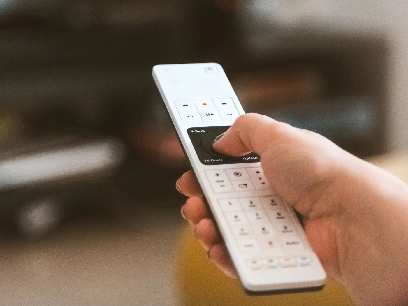 Een hand houdt een afstandsbediening van een televisie vast.