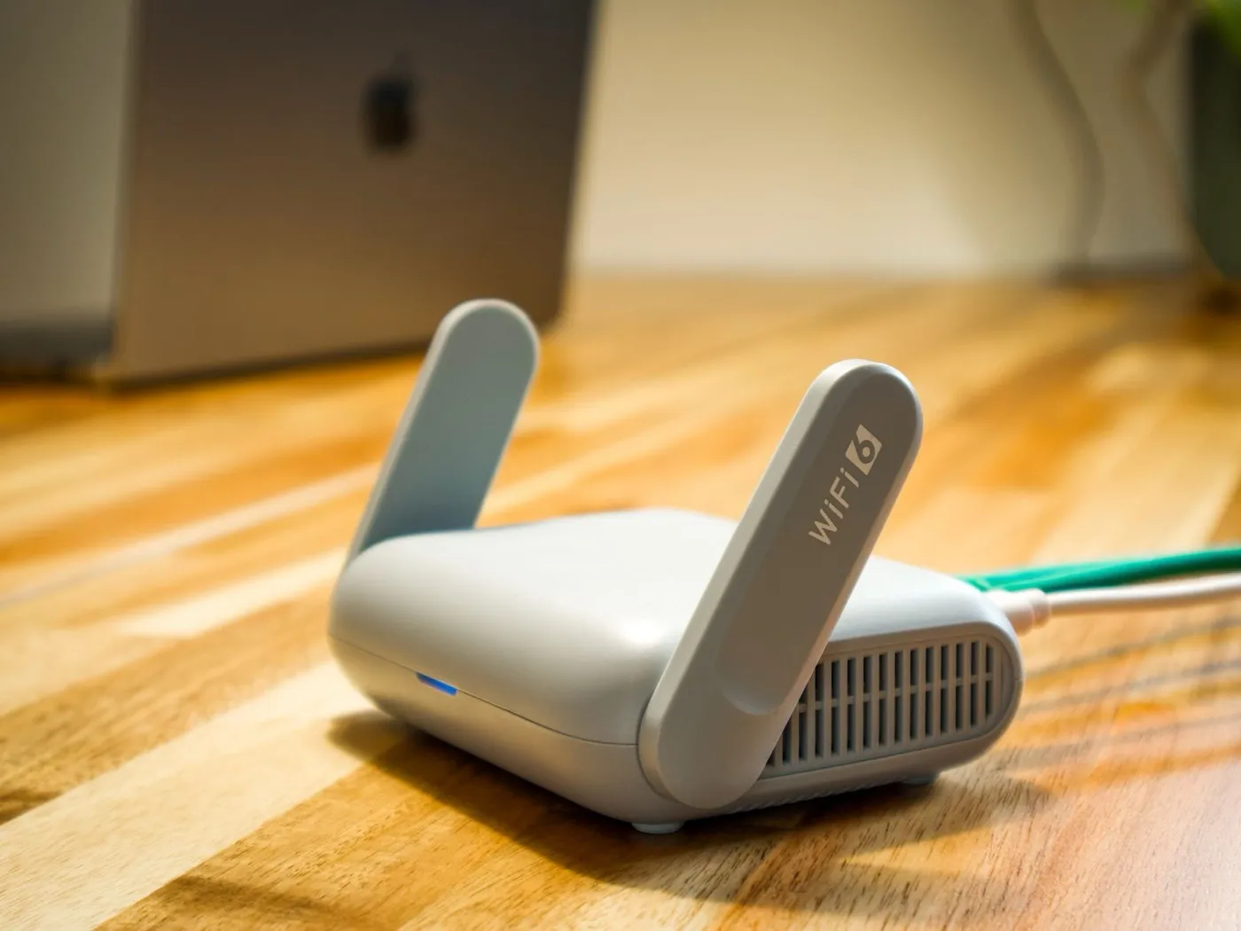 Een wifi-router met antennes op een houten bureau.